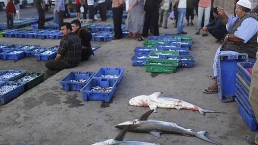Palestinians sell fish at a fish market in Gaza City May 22, 2013. Israel on Tuesday expanded the distance it permits Gaza fishermen to head out to sea, restoring a limit it cut in half two months ago in response to rocket fire from the Palestinian enclave. REUTERS/Suhaib Salem (GAZA - Tags: POLITICS CIVIL UNREST) - RTXZVXX