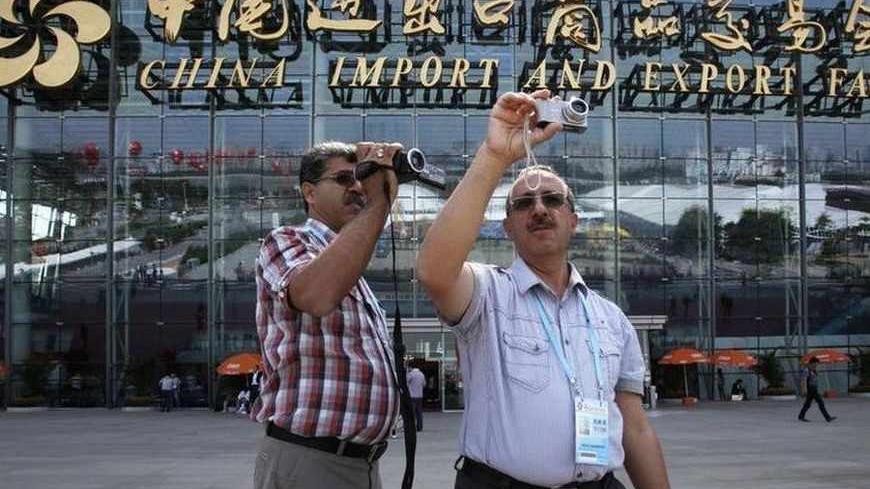 Visitors from Iran takes pictures outside an exhibition hall of China Import and Export Fair, also known as the Canton Fair, in the southern Chinese city of Guangzhou October 17, 2011. Exporters at China's largest trade show, the Canton Fair, say a darkening economic outlook in Europe and the United States is weighing on orders for Chinese-made goods from Western buyers, potentially boding ill for China's growth prospects. REUTERS/Bobby Yip (CHINA - Tags: BUSINESS) - RTR2SQQZ