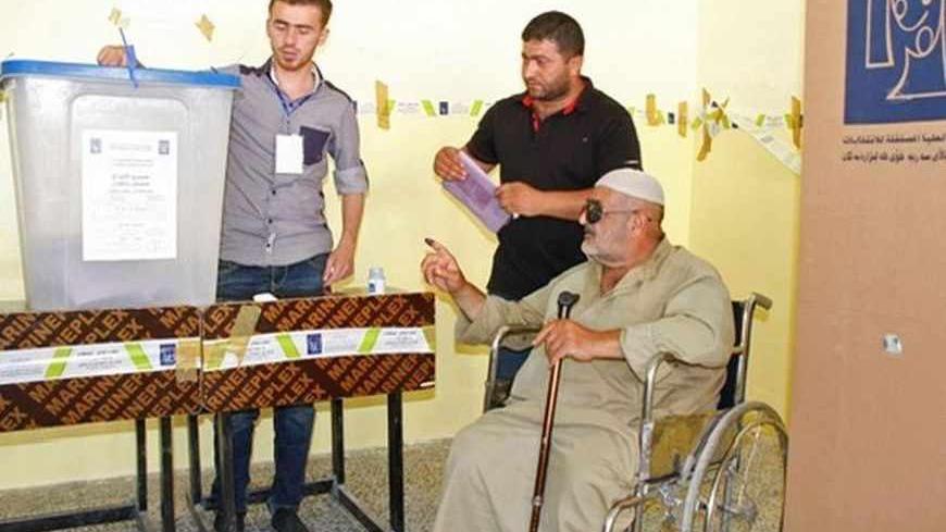 An elderly Iraqi man on a wheelchair receives help as he votes during Iraq's provincial elections at a polling station in Mosul, 390 km (242 miles) north of Baghdad, June 20, 2013. REUTERS/Khalid al-Mousuly  (IRAQ - Tags: ELECTIONS POLITICS) - RTX10UKC