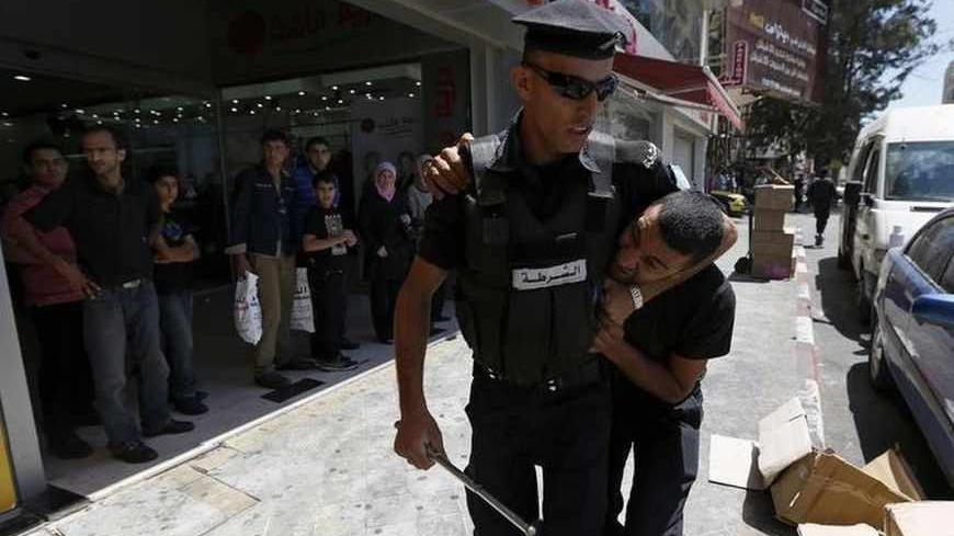 A Palestinian policeman detains a protester during a demonstration against the renewal of stalled peace talks with Israel, in the West Bank city of Ramallah, July 28, 2013. Israel was expected on Sunday to approve releasing more than 100 Arab prisoners as a step to renew stalled peace talks with the Palestinians ahead of plans to convene negotiators in Washington later this week. REUTERS/Mohamad Torokman (WEST BANK - Tags: POLITICS CIVIL UNREST) - RTX122FX