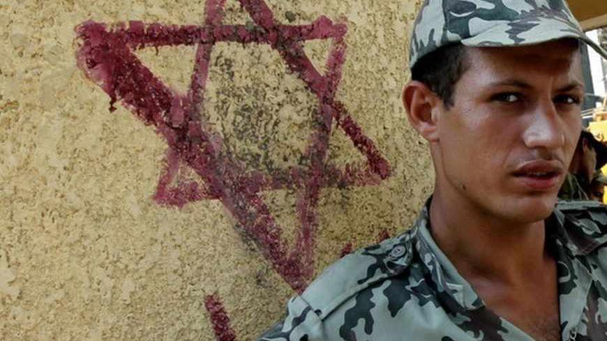 An Egyptian army soldier stands beside a star of David, on a wall surrounding the Israeli Embassy in Cairo September 4, 2011. Egypt has walled off Israel's embassy in Cairo after tensions between the two countries sparked a series of angry protests that reached a climax last month when a demonstrator scaled the building and removed the Israeli flag. As work began on the wall a few days ago, many Egyptians gathered nearby to show their displeasure. Picture taken September 4, 2011. REUTERS/Mohamed Abd El-Ghan