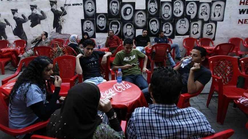 People chat near a wall decorated with portraits of protesters killed during the February revolution, at a coffee shop in Cairo October 17, 2011. REUTERS/Jamal Saidi      (EGYPT - Tags: SOCIETY) - RTR2SRES