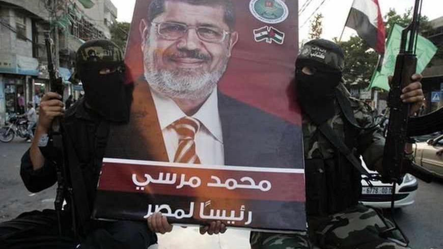 Hamas militants hold a poster depicting Mohamed Morsy of the Muslim Brotherhood as they celebrate in the street in Gaza City after he was declared Egypt's first democratic president June 24, 2012. Morsy's win was hailed by Hamas, the Islamist group governing Gaza and which is locked in a power-struggle with the West Bank-based, U.S.-backed Palestinian Authority of President Mahmoud Abbas. REUTERS/Mohammed Salem (GAZA - Tags: POLITICS ELECTIONS TPX IMAGES OF THE DAY MILITARY) - RTR343IV