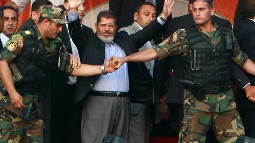 Egypt's Islamist President-elect Mohamed Mursi waves to his supporters while surrounded by his members of the presidential guard in Cairo's Tahrir Square, June 29, 2012. Mursi took an informal oath of office on Friday before tens of thousands of supporters in Cairo's Tahrir Square, in a slap at the generals trying to limit his power. REUTERS/Amr Abdallah Dalsh (EGYPT - Tags: POLITICS CIVIL UNREST TPX IMAGES OF THE DAY) - RTR34DDN