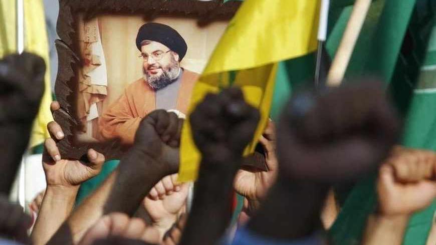 Protesters gesture as they carry Hezbollah and Amal movement flags and a picture of Lebanon's Hezbollah leader Sayyed Hassan Nasrallah at a protest against a film made in the United States that mocks the Prophet Mohammad, in Tyre, southern Lebanon September 19, 2012.  REUTERS/Ali Hashisho  (LEBANON - Tags: POLITICS CIVIL UNREST RELIGION) - RTR385NA