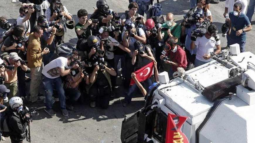 Media takes images of a protester holding a flag in front of a riot police vehicle during a protest at Taksim Square in Istanbul June 11, 2013. Turkish riot police moved on Tuesday into the central Istanbul square at the heart of 10 days of anti-government protests, firing tear gas and water cannon at hundreds of protesters armed with rocks and fireworks.  REUTERS/Osman Orsal (TURKEY  - Tags: POLITICS CIVIL UNREST)   - RTX10K7N