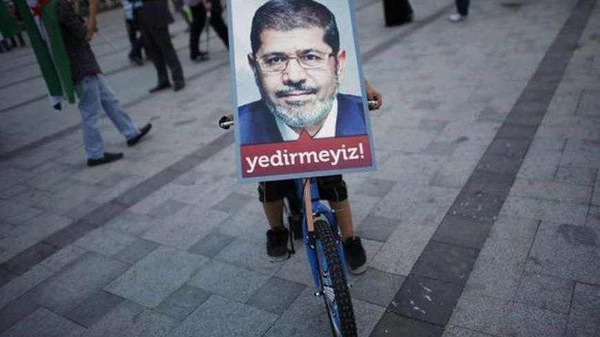 A boy balances a poster of Egypt's President Mohamed Mursi on his bicycle during a pro-Islamist demonstration in Istanbul July 1, 2013. Pro-Islamist groups held a demonstration in Istanbul in support of Mursi on Tuesday. Egypt's armed forces handed Islamist President Mohamed Mursi a virtual ultimatum to share power on Monday, giving feuding politicians 48 hours to compromise or have the army impose its own road map for the country. The slogan on the poster reads, " We will not let you victimise him". REUTER