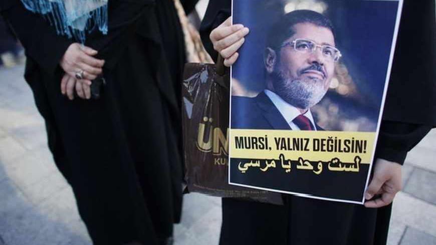 A woman holds a poster of Egypt's President Mohamed Mursi during a pro-Islamist demonstration in Istanbul July 1, 2013. Pro-Islamist groups held a demonstration in Istanbul in support of Mursi on Tuesday. Egypt's armed forces handed Islamist President Mohamed Mursi a virtual ultimatum to share power on Monday, giving feuding politicians 48 hours to compromise or have the army impose its own road map for the country. The slogan on the poster reads, "Mursi, you are not alone!" REUTERS/Murad Sezer (TURKEY - Ta