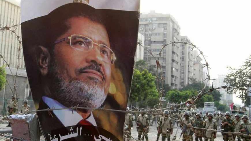 A portrait of deposed Egyptian President Mohamed Mursi is seen on barbed wire outside the Republican Guard headquarters in Cairo July 8, 2013. At least 51 people were killed on Monday when demonstrators enraged by the military overthrow of Egypt's elected Islamist president said the army opened fire during morning prayers outside the Cairo barracks where Mursi is believed to be held .REUTERS/Louafi Larbi (EGYPT - Tags: POLITICS CIVIL UNREST MILITARY) - RTX11GWI