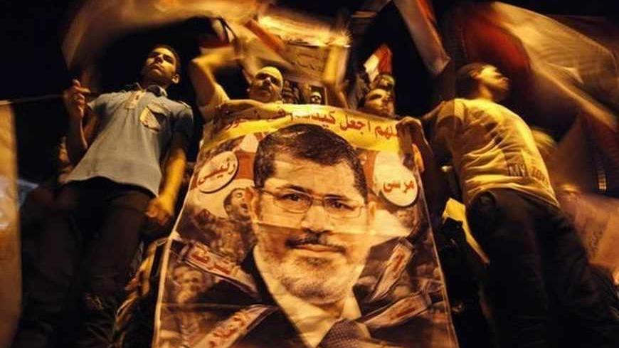 Members of the Muslim Brotherhood and supporters of deposed Egyptian President Mohamed Mursi hold a banner with his picture as they gather at the Rabaa Adawiya square, where they are camping, in Cairo July 12, 2013. Tens of thousands of Egyptians packed into squares and marched along streets in Cairo on Friday to protest against the military overthrow of Islamist President Mursi, and the United States called for the first time for him to be freed. REUTERS/Mohamed Abd El Ghany (EGYPT - Tags: POLITICS CIVIL U