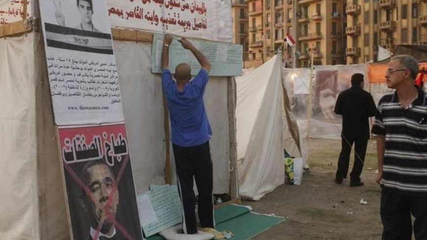 A protester hangs placards on his tent as a crossed-out picture of U.S. President Barack Obama is seen, in Tahrir square, Cairo, July 15, 2013. The first senior U.S. official to visit Egypt since the army toppled its elected president was snubbed by both Islamists and their opponents on Monday.
 Deputy Secretary of State William Burns arrived in a divided capital where both sides are furious at the United States, the superpower which supports Egypt with $1.5 billion in annual aid, mostly for the army that d