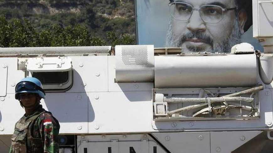 An Indonesian soldier from the United Nations Interim Forces in Lebanon (UNIFIL) stands near a U.N. armoured vehicle as a picture of Lebanon's Hezbollah leader Sayyed Hassan Nasrallah is seen behind him in the southern Lebanese village of Adaisseh July 24, 2013. Europe's decision to blacklist Hezbollah's "military wing" was triggered by the Lebanese movement's growing role in Syria, but the partial ban may have little practical impact due to fears of destabilising Lebanon and the wider Middle East.    REUTE