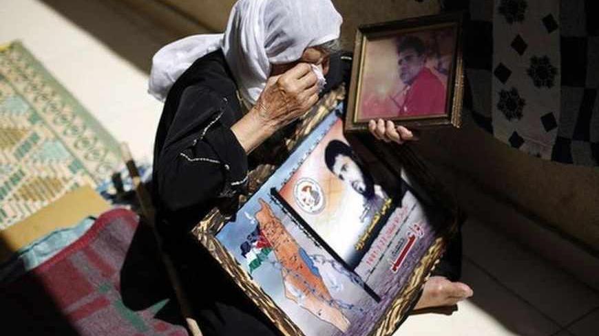 Rayya, mother of Palestinian Fares Baroud, who has been held prisoner by Israel for 22 years, wipes her tears as she holds his picture after hearing news on the possible release of her son in her house at Shati refugee camp in Gaza City July 28, 2013. Baroud was expected to be among more than 100 Arab prisoners to be released as a step to renew stalled peace talks with the Palestinians ahead of plans to convene negotiators in Washington later this week.  Israeli ministers have yet to vote on the releases. R