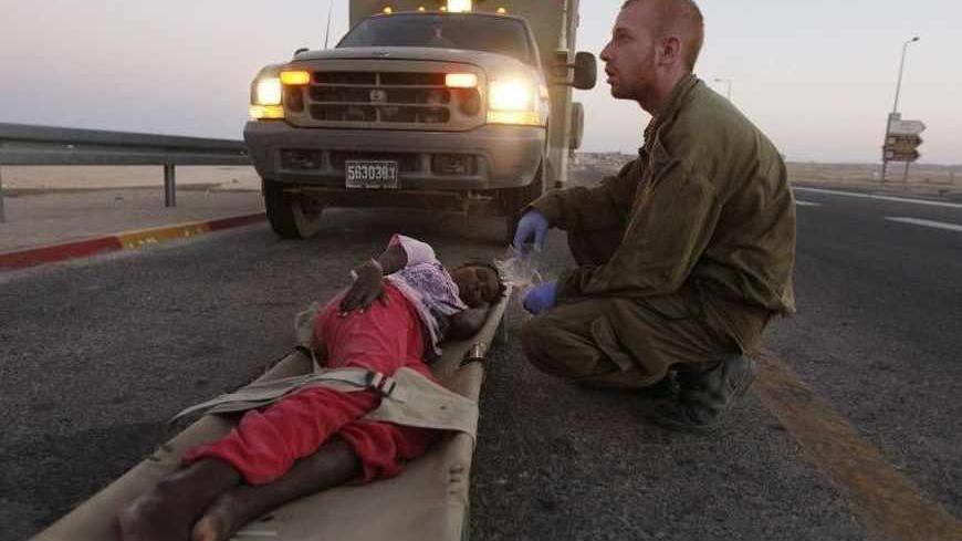 An Israeli soldier gives medical treatment to a young  Sudanese migrant suffering from dehydration outside the Sagi Mount military base near the Israeli-Egypt border September 21, 2012. Three armed militants slipped into Israel from Egypt's Sinai peninsula on Friday, killing an Israeli soldier and wounding another before being shot dead, the army said.  The commander of Israeli troops in the region said the gunmen ambushed soldiers who had just intercepted some African migrants trying to cross into Israel a