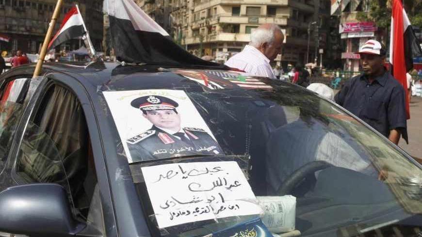 A man with a poster of the chief of Egypt's armed forces General Abdel Fattah al-Sisi on his car, talks to a protester in Tahrir square, in Cairo, July 9, 2013. Sign reads, "I love Egypt".   REUTERS/ Asmaa Waguih (EGYPT - Tags: POLITICS MILITARY CIVIL UNREST) - RTX11HPZ