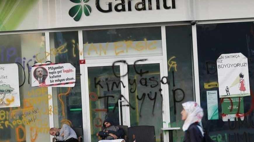 Protesters sleep outside a branch of Garanti Bank at Taksim Square in central Istanbul June 3, 2013. Turkish protesters clashed with riot police into the early hours of Monday with some setting fire to offices of the ruling AK Party as the fiercest anti-government demonstrations in years entered their fourth day. Turkey's streets were calm in the morning after a night of noisy protests and violence in major cities. The posters read, "A tree died, a nation awoke" (L), "Come with millions Tayyip" (2nd L), "Yo