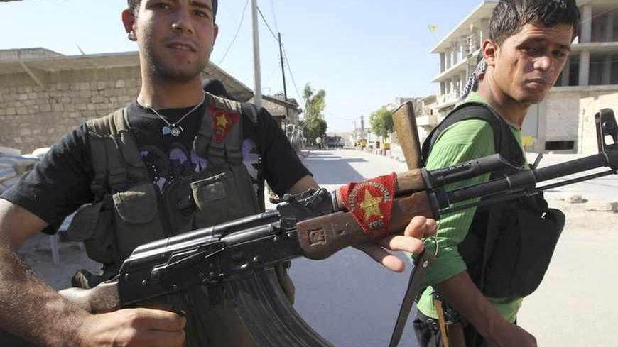 A Kurdish fighter from the Popular Protection Units (YPG) shows his weapon decorated with his party's flag, as a fellow fighter looks on in Aleppo's Sheikh Maqsoud neighbourhood, June 7, 2013. Kurdish fighters from the YPG joined the Free Syrian Army to fight against forces loyal to Syria's President Bashar al-Assad. Picture taken June 7, 2013. REUTERS/Muzaffar Salman  (SYRIA - Tags: CIVIL UNREST POLITICS CONFLICT) - RTX10UT2