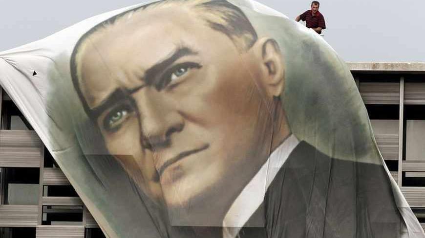 A worker fixes a giant portrait of Mustafa Kemal Ataturk at the top of the Ataturk Cultural Center in Istanbul's Taksim Square June 28, 2013.  REUTERS/Osman Orsal (TURKEY - Tags: POLITICS CIVIL UNREST TPX IMAGES OF THE DAY) - RTX114YL