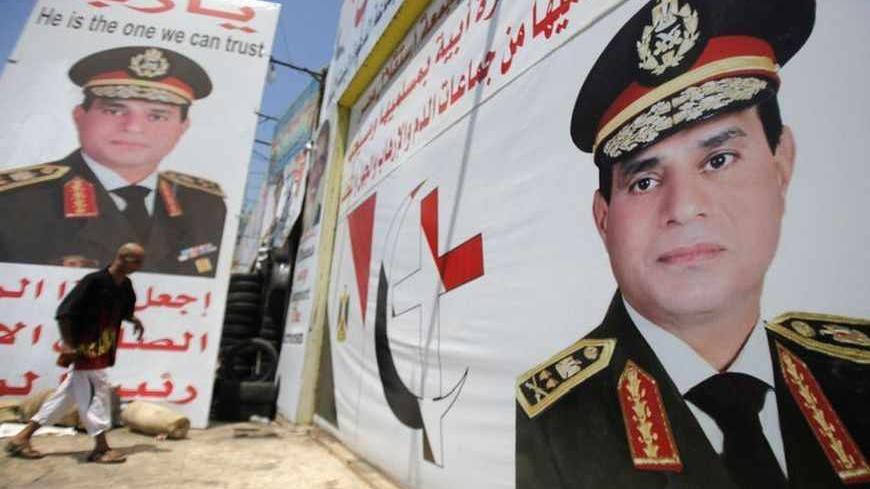 Salah Abdel Moneim, 40, an Anti-Mursi supporter of Egypt's army, walks in front of his shop, plastered with huge posters of Egypt's army chief General Abdel Fattah al-Sisi in downtown Cairo August 7, 2013. Egypt's presidency said on Wednesday that diplomatic efforts to end the country's political turmoil had failed and warned that the Muslim Brotherhood of ousted President Mohamed Mursi would be held responsible for the consequences. In a statement, interim President Adly Mansour's office said the period of