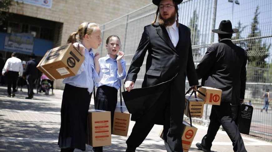 An ultra-Orthodox Jewish man walks out with his children after collecting gas mask kits at a distribution point in Jerusalem August 28, 2013. Thousands of Israelis on Wednesday continued to queue up for gas masks or ordered them by phone, spurred on by fears that any Western military response to last week's alleged chemical weapons attack in Syria could ensnare their own country in war. Israel also deploying all of its missile defences as a precaution against possible Syrian retaliatory attacks should Weste