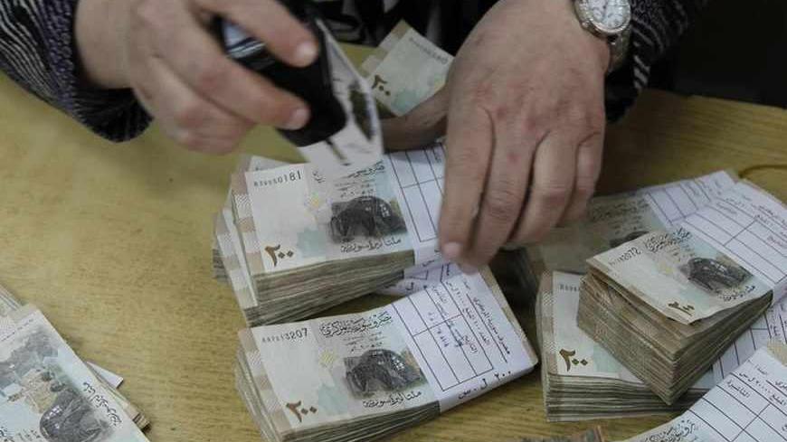An employee stamps stacks of Syrian pound notes at the Syrian central bank in Damascus April 23, 2013. Picture taken April 23, 2013.        To match SYRIA-CURRENCY/        REUTERS/Khaled al-Hariri (SYRIA - Tags: POLITICS CONFLICT BUSINESS) - RTXYYC3