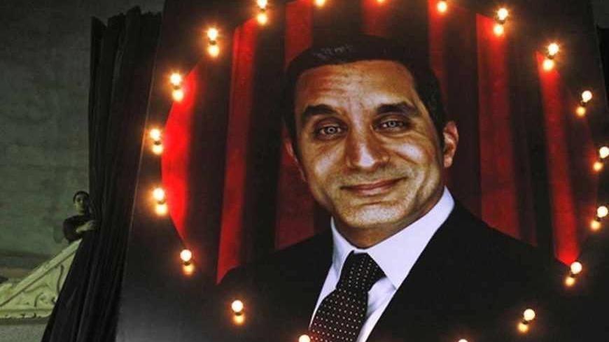 A worker lifts curtains in a theatre to reveal a picture of Egyptian satirist Bassem Youssef for his comic show "Al-Bernameg" (The Programme), in Giza January 15, 2013. REUTERS/Asmaa Waguih (EGYPT - Tags: POLITICS ENTERTAINMENT) - RTR3CI1L