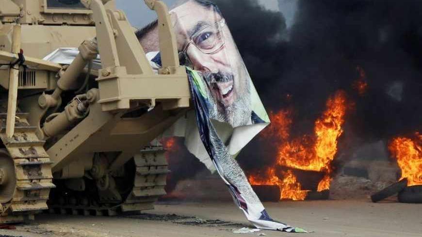 A torn poster of deposed Egyptian President Mohamed Mursi is pictured as riot police clear the area of his supporters at Rabaa Adawiya square, where the protesters had been camping, in Cairo August 14, 2013. At least 95 Egyptians were killed on Wednesday after security forces moved in on protesters demanding the reinstatement of Mursi, and the government imposed a state of emergency as unrest swept the most populous Arab nation. REUTERS/Mohamed Abd El Ghany (EGYPT - Tags: POLITICS CIVIL UNREST TPX IMAGES OF
