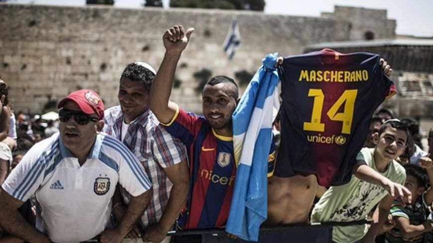 Fans of FC Barcelona cheer as the team leaves the Western Wall, Judaism's holiest prayer site, in Jerusalem's Old City August 4, 2013. The Spanish league champions are making a brief stopover in Israel and the Palestinian territories en-route to a pre-season tour of Asia. REUTERS/Oliver Weiken/Pool (JERUSALEM - Tags: POLITICS SPORT RELIGION SOCCER) - RTX12A38