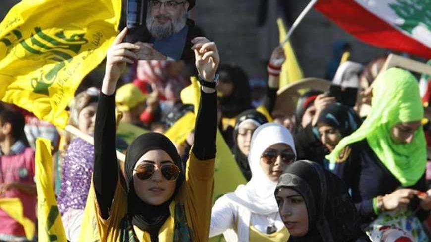 Supporters of Lebanon's Hezbollah leader Sayyed Hassan Nasrallah carry his picture and wave Hezbollah and Lebanese flags as they listen to him via a screen during a rally on the 7th anniversary of the end of Hezbollah's 2006 war with Israel, in Aita al-Shaab village in southern Lebanon, August 16, 2013. Nasrallah renewed his commitment on Friday to the battle in Syria, where the Shi'ite militant group has been fighting alongside President Bashar al-Assad's forces, saying he was ready to go himself if needed