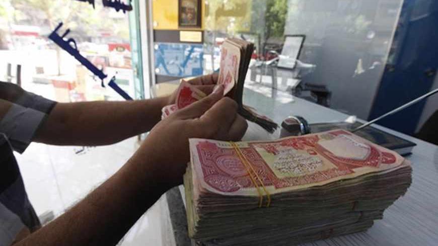 A customer counts Iraqi dinars at a money changer in Baghdad October 1, 2012. Many Iraqis have lost faith in their dinar currency but to some foreign speculators, it promises big profits. The contrast underlines the uncertainties of investing in Iraq as the country recovers from years of war and economic sanctions. Picture taken October 1, 2012. To match IRAQ-ECONOMY/DINAR  REUTERS/Saad Shalash (IRAQ - Tags: BUSINESS POLITICS) - RTR38QU1