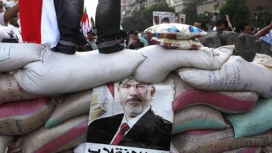 A poster of deposed Egyptian President Mohamed Mursi is seen on a make-shift barrier of sand bags made by members of the Muslim Brotherhood and Musi supporters to protect the sit-in area of Rab'a al- Adawiya Square, where they are camping, on the first day of the Eid al-Fitr holiday after the end of the fasting month of Ramadan, in Cairo August 8, 2013. Islamist supporters of Mursi began marching to demand his restoration on Thursday after the military-led authorities that removed him held off from carrying