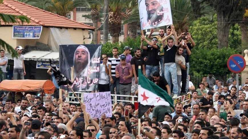 Protesters chant slogans against Syrian President Bashar al-Assad as they hold a poster of deceased al-Qaeda leader Osama bin Laden (top), during a protest in solidarity with Syria's anti-government protesters, in the port-city of Tripoli in north Lebanon October 7, 2011.                                       REUTERS/Omar Ibrahim     (LEBANON - Tags: POLITICS CIVIL UNREST) - RTR2SCOJ