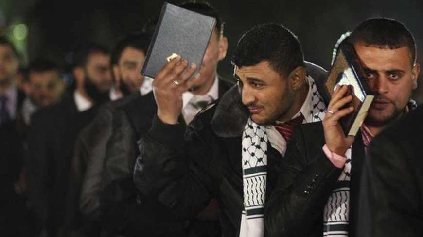 Palestinian grooms hold copies of the Koran during a mass wedding for 500 couples, funded by a local charitable organisation and in co-ordination with Hamas, in Gaza City March 8, 2012. REUTERS/ Suhaib Salem (GAZA - Tags: SOCIETY) - RTR2Z1WC