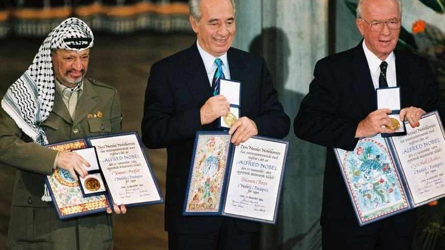File photograph of Palestinian President Arafat, Israel's Perez and Israeli Prime Minister Rabin showing their Nobel Peace Prize in Oslo.  Palestinian President Yasser Arafat was in a coma and in critical condition in the intensive care unit at a French military hospital after his health suddenly deteriorated, aides said November 4, 2004. Palestinian President Yasser Arafat, (L) Israel's Shimon Perez (C) and Israeli Prime Minister Yitzhak Rabin show their Nobel Peace Prize in Oslo in this December 10, 1994 