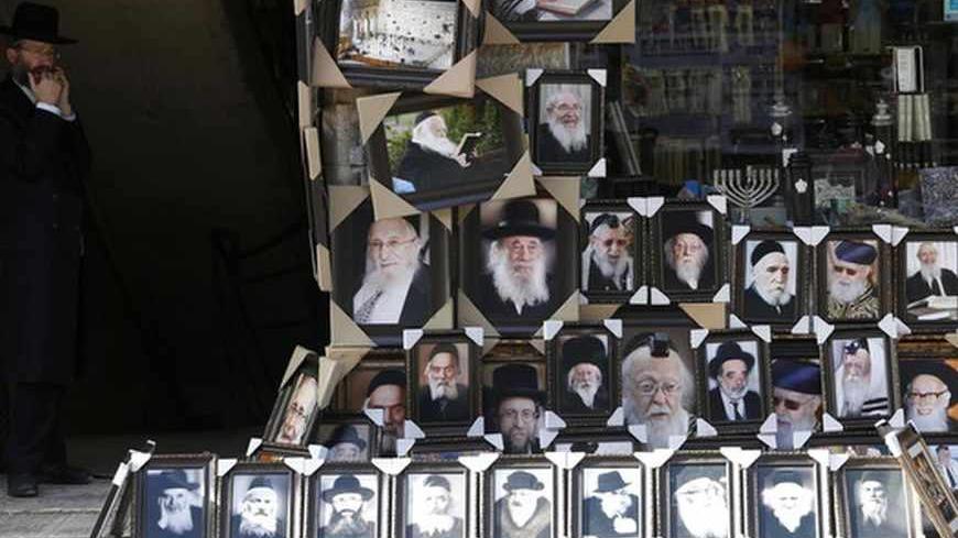 An ultra-Orthodox Jewish man stands near a display of pictures of Rabbis and religious leaders for sale outside a shop in Jerusalem's Mea Shearim neighbourhood June 4, 2013. Often living in de-facto ghettos of their own making, the majority of Haredi men are allowed to shun the army and dedicate their life to religious study, living off donations, state benefits and the often meagre wages of wives. In a country where most 18-year-old Jewish men and women are conscripted such treatment is causing growing res