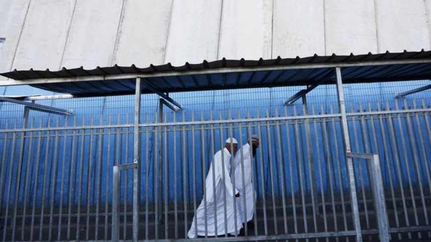 Palestinians walk near the controversial Israeli barrier as they cross into Jerusalem at an Israeli checkpoint in the West Bank town of Bethlehem July 26, 2013. Israeli and Palestinian officials put forward clashing formats for peace talks due to resume in Washington on Monday for the first time in nearly three years after intense U.S. mediation. It is unclear how the United States hopes to bridge the core issues in the dispute, including borders, the future of Jewish settlements on the West Bank, the fate 