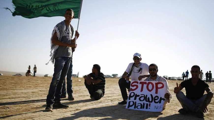 A protester holds a placard as another holds an Islamic movement flag during a demonstration to show their solidarity with Bedouin citizens, near the Bedouin town of Rahat in southern Israel August 1, 2013. Hundreds demonstrated against an Israeli cabinet plan to relocate some 30,000 Bedouin citizens who live in unrecognized villages in Israel's southern Negev desert and relocate them to towns built by the government. REUTERS/Amir Cohen (ISRAEL - Tags: POLITICS CIVIL UNREST) - RTX127DJ