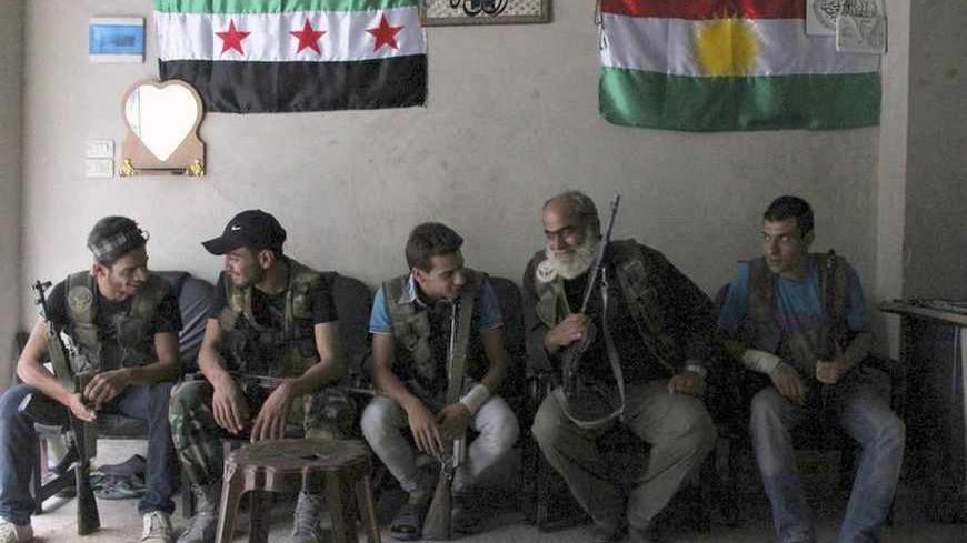 Free Syrian Army fighters sit together with Syrian Kurdish fighters inside a house in Ashrafieh, Aleppo August 5, 2013. The Syrian opposition flag (L) hangs next to the Kurdish flag on the wall behind. REUTERS/Aref Hretani (SYRIA - Tags: CONFLICT POLITICS TPX IMAGES OF THE DAY) - RTX12B7O