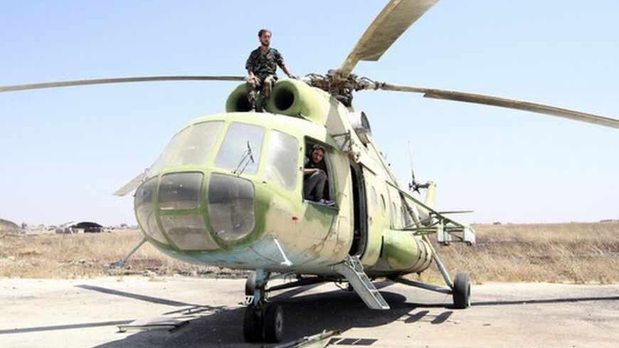 Free Syrian Army fighters are seen on a Russian-made helicopter that belonged to the Syrian Army at the Minnig Military Airport, after it was seized by the rebels August 11, 2013. Syrian rebels captured the main military airport near the border with Turkey on August 6, consolidating their hold on a key supply route north of the city of Aleppo, opposition activists said. REUTERS/Mahmoud Hassano (SYRIA - Tags: CIVIL UNREST CONFLICT MILITARY TPX IMAGES OF THE DAY) - RTX12H8L