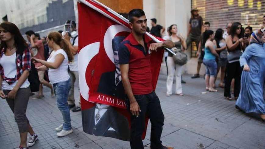 A street vendor sells Turkish flags bearing images of Mustafa Kemal Ataturk, the first president of Turkey, as demonstrators gather for an anti-government protest on the main Istiklal Street in central Istanbul August 3, 2013.  REUTERS/Murad Sezer (TURKEY - Tags: POLITICS CIVIL UNREST) - RTX129LP