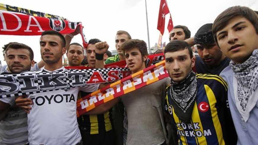 Fans of Besiktas (Black-White), Galatasaray (Yellow-Red) and Fenerbahce (Yellow-Blue) pose during an anti-government protest at Taksim Square in central Istanbul June 2, 2013. Days of anti-government protest in Turkey have achieved one feat that has eluded the authorities for years: uniting the fiercely rival and sometimes violent supporters of Istanbul's "Big Three" football clubs. Besiktas, Galatasaray and Fenerbahce fans have come together in new-found solidarity during five days of demonstrations agains