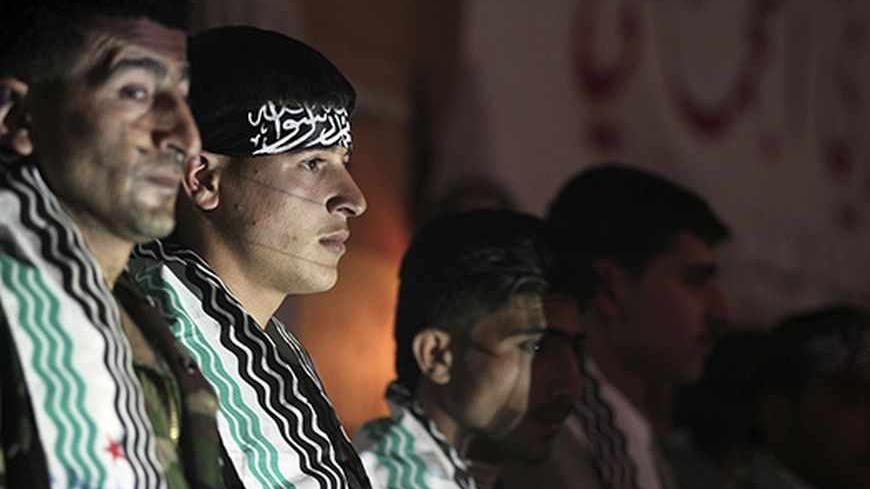 Nader, a 20-year-old fighter of the first batch of the Al-Tawhid Brigade, stands beside other grooms during his wedding ceremony in Aleppo's countryside city of Al-Bab March 15, 2013. A mass wedding took place for fourteen members of the first batch of the Al-Tawhid Brigade, which operates under the Free Syrian Army, in Al-Bab. Picture taken March 15, 2013. REUTERS/Giath Taha (SYRIA - Tags: CIVIL UNREST CONFLICT SOCIETY) - RTR3F2PX