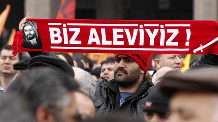 A protester holds a banner reading "we are alevi" as he and many others wait to hear the decision of the court in front of a courthouse in Ankara March 13, 2012. Turkish police fired tear-gas and water cannon to disperse hundreds protesting on Tuesday against the dropping of a case against five people charged with killing 37 writers and liberals in a 1993 hotel fire set off by Islamist rioters.The opposition accused Prime Minister Tayyip Erdogan and his AK Party, which emerged from a series of banned Islami