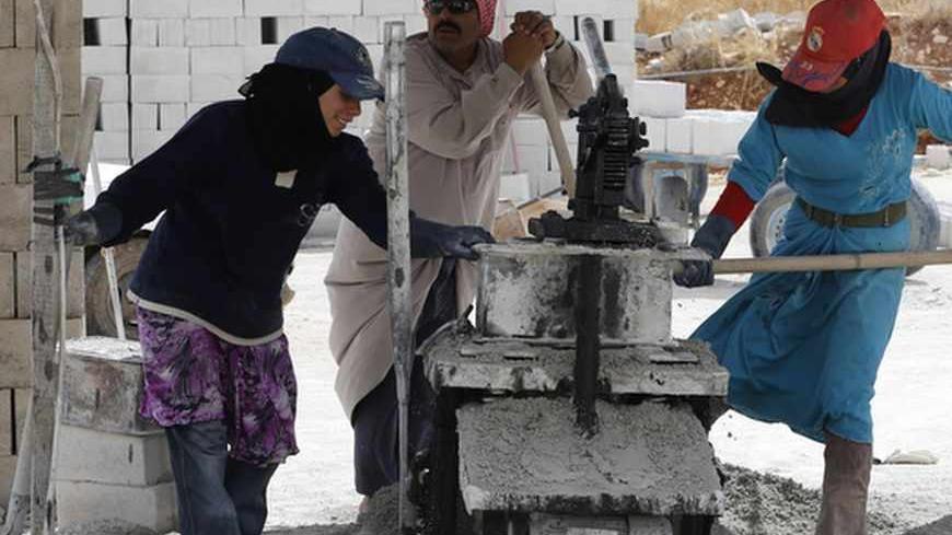Syrian refugees work to help produce concrete blocks in Bekaa Valley, Lebanon September 21, 2013. Female Syrian refugees of the Masari family, who fled from the Aleppo countryside in Syria a year ago, worked alongside their husbands in the concrete producing factory owned by a Lebanese man, according to the workers. Each Syrian couple produces 700 concrete blocks a day and earns a combined wage of $50, the refugees said. Picture taken September 21, 2013.    REUTERS/Jamal Saidi (LEBANON - Tags: BUSINESS CONS
