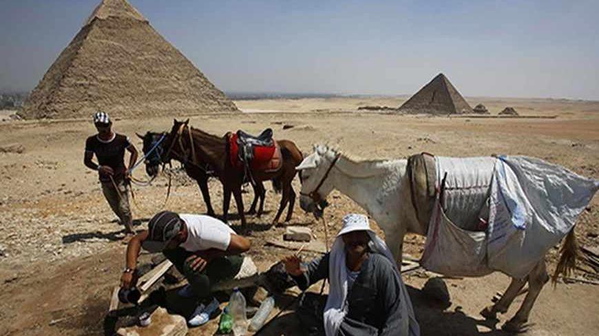 Camel guides drink tea as they wait for customers at the Pyramids Plateau in Giza Pyramids, on the outskirts of Cairo August 26, 2013. REUTERS/Youssef Boudlal (EGYPT - Tags: SOCIETY TRAVEL ANIMALS) - RTX12XEU