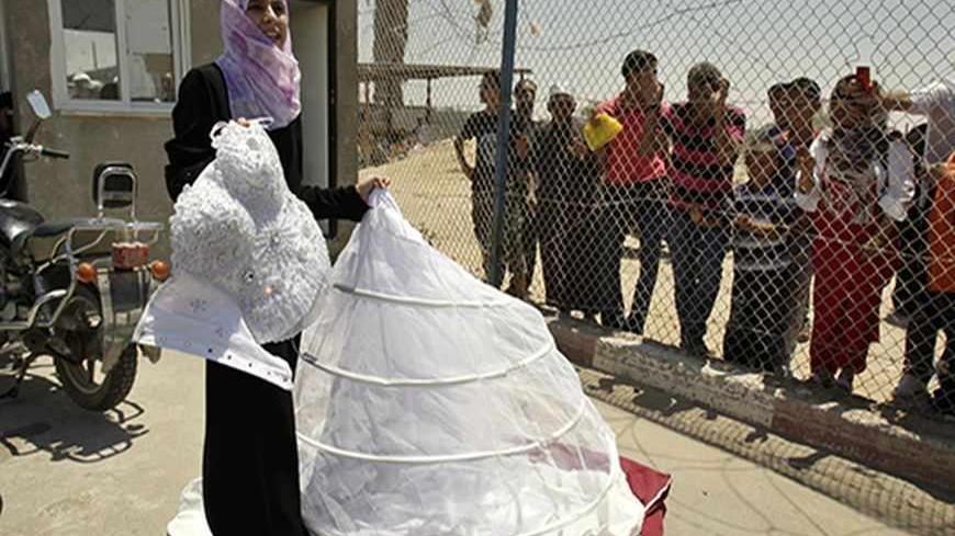 Palestinian Doa'a Abu Mosabeh holds her wedding dress as she tries to cross into Egypt at Rafah border crossing in the southern Gaza Strip June 21, 2011. Abu Mosabeh's wedding is set for Thursday June 23 in Qatar and she has been unable to leave Gaza Strip due to the slow passage movement at Rafah border crossing with Egypt.   REUTERS/Ibraheem Abu Mustafa (GAZA - Tags: POLITICS) - RTR2NWY7