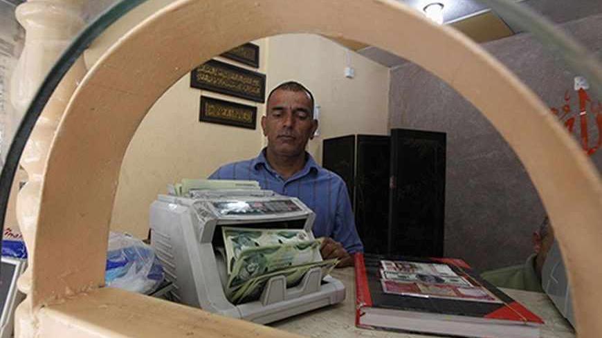 A man counts wads of Iraqi dinars using a money counting machine at a currency exchange shop in Baghdad October 1, 2012. Many Iraqis have lost faith in their dinar currency but to some foreign speculators, it promises big profits. The contrast underlines the uncertainties of investing in Iraq as the country recovers from years of war and economic sanctions. Picture taken October 1, 2012. To match IRAQ-ECONOMY/DINAR  REUTERS/Saad Shalash (IRAQ - Tags: BUSINESS POLITICS) - RTR38QU3