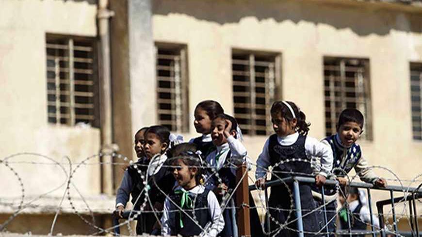 Students inside an elementary school watch a passing demonstration of daily-paid workers asking for full-time jobs in Basra, 420 km (260 miles) southeast of Baghdad, March 7, 2012.    REUTERS/Atef Hassan (IRAQ - Tags: EDUCATION) - RTR2YZ4M