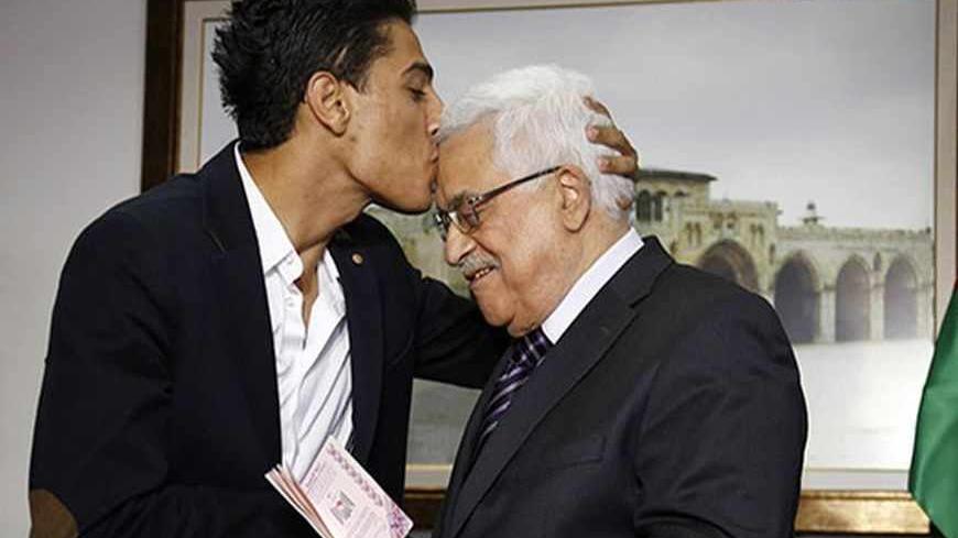 "Arab Idol" Mohammed Assaf (L) kisses Palestinian President Mahmoud Abbas as he hands him a diplomatic Palestinian Authority passport during their meeting in the West Bank city of Ramallah July 1, 2013. Assaf, the 22-year-old from the Gaza Strip who won the popular pan-Arab song contest last month met Abbas on Monday before performing in Ramallah. REUTERS/Mohamad Torokman (WEST BANK - Tags: ENTERTAINMENT POLITICS) - RTX11973