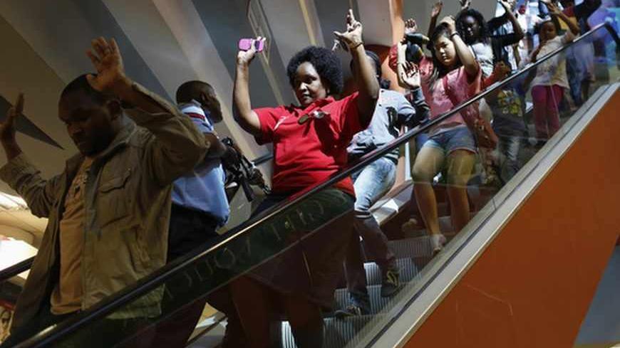 Civilians escape an area at the Westgate Shopping Centre in Nairobi September 21, 2013. Gunmen stormed the shopping mall in Nairobi on Saturday killing at least 20 people in what Kenya's government said could be a terrorist attack, and sending scores fleeing into shops, a cinema and onto the streets in search of safety. Sporadic gun shots could be heard hours after the assault started as soldiers surrounded the mall and police and soldiers combed the building, hunting down the attackers shop by shop.  REUTE